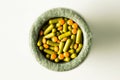 Yellow capsules and orange pills with mortar pestles on white background. Royalty Free Stock Photo