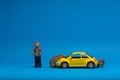 Chisinau 20.02.2020Yellow car figurine under a heap of golden coins next to a man made from plasticine which is holding a a house. Royalty Free Stock Photo