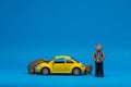 Chisinau 20.02.2020:Yellow car figurine under a small heap of coins next to a man made from plasticine which is holding a a house. Royalty Free Stock Photo