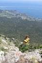 Yellow car over the cliff lifts people to the top, cable car to the mountain