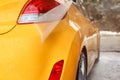 Yellow car rear light and bumper washed in self serve carwash, w Royalty Free Stock Photo