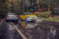 Yellow car rides in the yard on a wet road in the rain . Beautiful splashes of water from under the wheels. Royalty Free Stock Photo