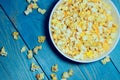 Yellow caramelized popcorn on a blue wooden background.  Fast food, junk food. Royalty Free Stock Photo