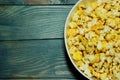 Yellow caramelized popcorn on a blue wooden background.  Fast food, junk food. Royalty Free Stock Photo