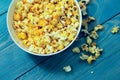 Yellow caramelized popcorn on a blue wooden background.  Fast food, junk food. Royalty Free Stock Photo