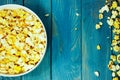 Yellow caramelized popcorn in white bowl over blue wooden background.  Fast food, junk food. Royalty Free Stock Photo