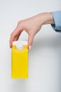 Yellow carton box with a cap in a female hand. White background Royalty Free Stock Photo