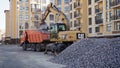 Yellow CAT excavator loader works on a construction site with gravel. Loading gravel onto a truck. Road construction site.