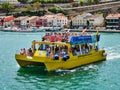 A yellow catamaran full of people set off on a sea cruise from the port of Mahon, Menorca