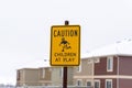Yellow Caution Children At Play sign against blurry building and cloudy sky Royalty Free Stock Photo