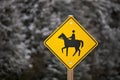 Yellow Caution Horse Riding Sign in a Rural Setting in Winter Isolated against a Snowy Forest Royalty Free Stock Photo