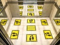 Yellow caution signs on elevator floor to keep social distancing between passengers