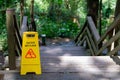 Yellow Caution slippery wet floor sign outdoors near wooden staircase Royalty Free Stock Photo