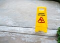 Yellow caution slippery wet floor sign with slippery person warning icon on wet concrete floor background. Royalty Free Stock Photo