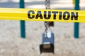 Yellow caution tape closes swings in a city park. Royalty Free Stock Photo