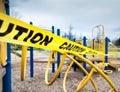 Yellow caution tape surrounding climbing apparatus in closed public playground during Coronavirus Covid-19 pandemic