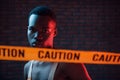 Yellow caution tape and uniform. Futuristic neon lighting. Young african american man in the studio Royalty Free Stock Photo