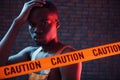 Yellow caution tape and uniform. Futuristic neon lighting. Young african american man in the studio Royalty Free Stock Photo