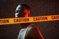 Yellow caution tape and uniform. Futuristic neon lighting. Young african american man in the studio Royalty Free Stock Photo