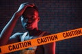 Yellow caution tape and uniform. Futuristic neon lighting. Young african american man in the studio Royalty Free Stock Photo