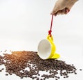 The yellow ceramic coffee cup was tied and hanging by red rope from human hand,plenty of coffee beans on background Royalty Free Stock Photo