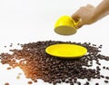 The yellow ceramic coffee cup was turn over by human hand,plenty of coffee beans on background Royalty Free Stock Photo