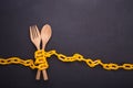 Yellow chain locked around the wooden spoon and fork on black st