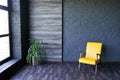 Yellow chair near window in modern dark interior with black brick wall, copy space Royalty Free Stock Photo