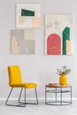 Yellow chair next to wooden coffee table with flowers in vase Royalty Free Stock Photo