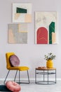 Yellow chair with round pillow next to wooden coffee table with flowers in vase Royalty Free Stock Photo