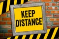 Yellow chalkboard in front of a clinker wall with message Keep Distance - social distancing Royalty Free Stock Photo