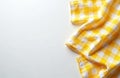 Yellow checkered cloth lies on white surface. Fabric is folded. Cloth adds a warm touch for kitchen and dining space. Textile Royalty Free Stock Photo