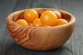 Yellow cherry tomatoes in olive bowl on wood table Royalty Free Stock Photo