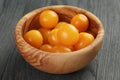 Yellow cherry tomatoes in olive bowl on wood table Royalty Free Stock Photo