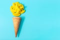 Yellow chewing candy with waffle cone on the blue background, copy space