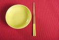 Yellow chopsticks and bowl on red table place setting mat. Royalty Free Stock Photo