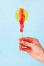 Yellow circle lollypop with droping sugar paste in hand. The concept of intimate depilation - bikini zone, hair removal with hot