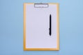 A yellow clipboard and a black pen with blank white paper on a blue background