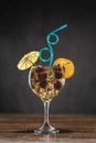 Yellow cocktail with cherry in a glass standing on a wooden table, decorated with a slice of grapefruit