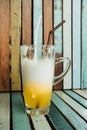 Yellow cocktail glass with straw stands on background colorful wooden boards Royalty Free Stock Photo