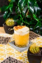 Yellow cocktail with white protein foam in a beautiful old fashion glass, decorated with a mango skewer