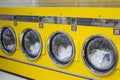 Yellow coin washing machines with laundry in it