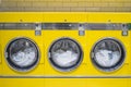 Yellow coin washing machines with laundry in it