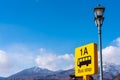 Yellow color bus stop sign with blue sky and snow mountain in background Royalty Free Stock Photo