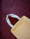 Yellow color eco bag with White handle on brown background