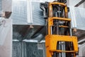 Yellow colored rusty old forklift is in the storage with heavy material