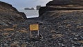 Yellow colored warning sign at the entrance to Kirkjufjara on the Atlantic coast on DyrhÃÂ³laey in southern Iceland.