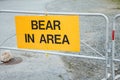 Yellow colored warning sign Bear In Area informing about wildlife activity in the area near trail in Park