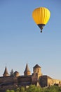 Yellow colorful hot air balloon flying in blue sky over roofs of city Royalty Free Stock Photo