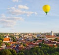 Yellow colorful hot air balloon flying in blue sky over roofs of city Royalty Free Stock Photo